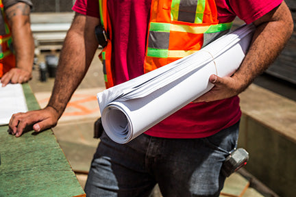 Construction worker holding a roll of building plans.