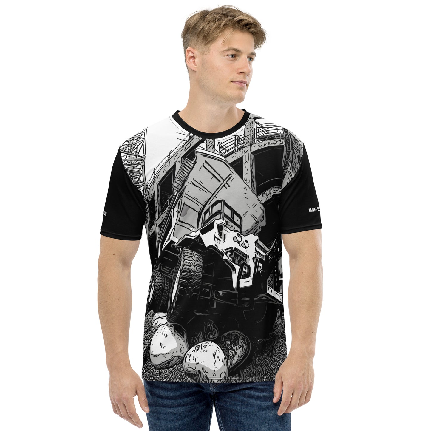 A man wearing our Construction Grind Big Dump all-over print short-sleeved t-shirt in our black and white style, shown from the front. The main graphic features a large dump truck actively crawling over rough terrain at a construction site in front of a building under construction, highlighting dynamic construction imagery. The design is printed in vibrant colors on a premium, all-over print tee.