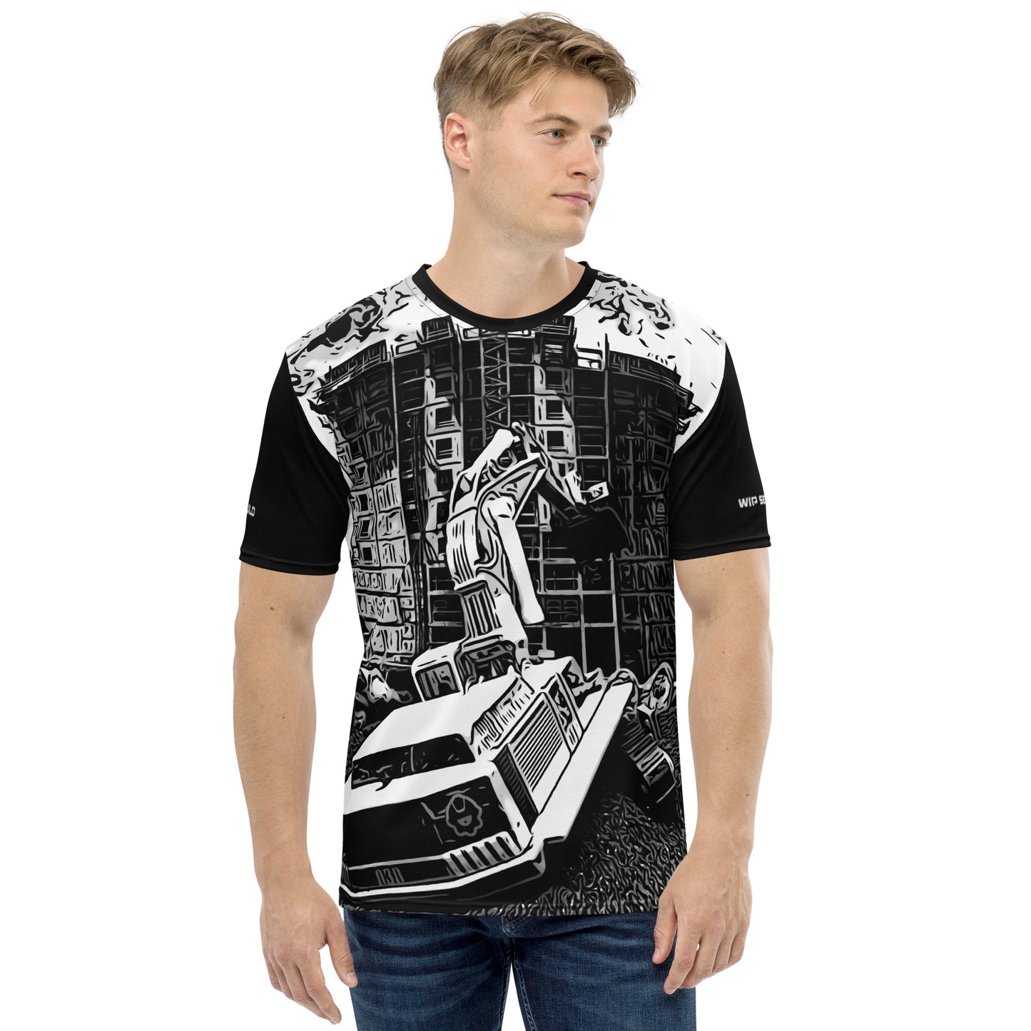 A man wearing our Construction Grind Dig Alert all-over print short-sleeved t-shirt in our black and white style, shown from the front. The main graphic features a large excavator actively digging rough terrain at a construction site in front of a building under construction, highlighting dynamic construction imagery. The design is printed in vibrant colors on a premium, all-over print tee.