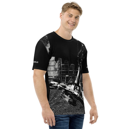 A man wearing our Construction Grind Super Scooper all-over print short-sleeved t-shirt in black and white style, shown from the right-hand view. The image reveals the detailed main graphic of an excavator in action on a construction site, and the right sleeve displays a white 'I Build' graphic. The design emphasizes bold construction imagery on a premium tee.